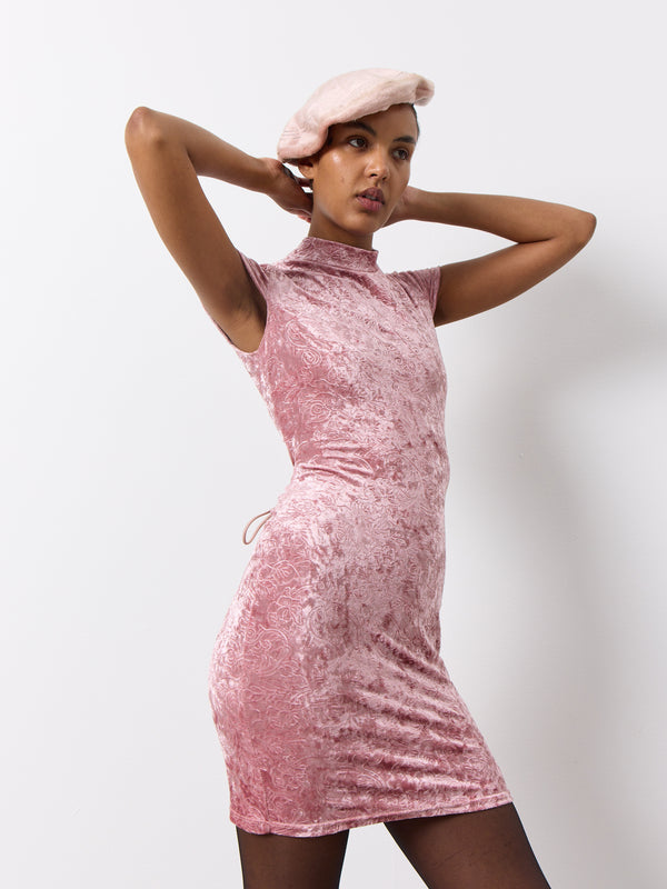 The Pink strappy back dress is designed for a sleek, fitted look with a lovely floral pattern and stretchy velvet material. It features a unique tie-back design and intricate floral details, as well as a turtle neck collar with a secure two button closure.